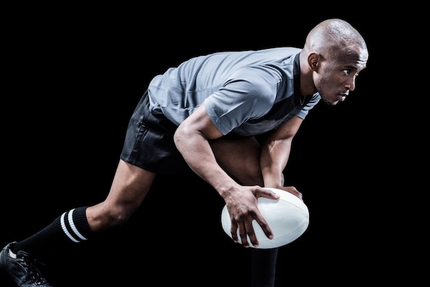 Determined athlete bending while playing rugby