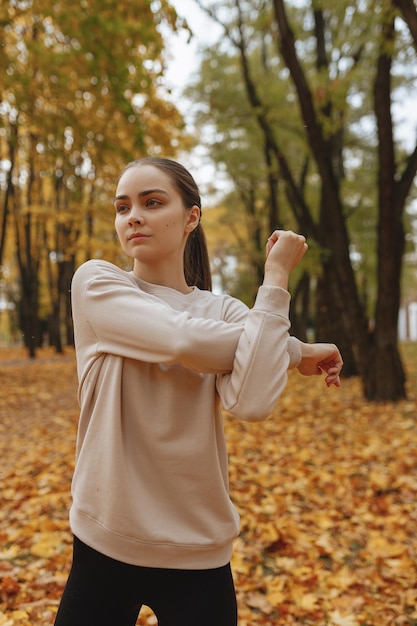 Determined fit female runner stretching arms and warming up before training in nature