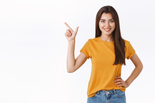 Determined, good-looking motivated female professional know what you need, pointing upper left corner smiling assertive and confident, hold hand on hip, standing white background assured