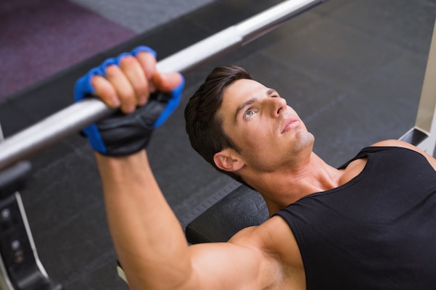 Determined muscular man lifting barbell in gym