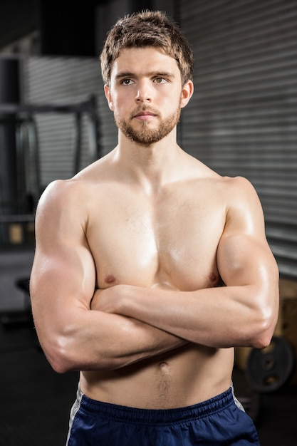 Determined shirtless man with arms crossed at the gym