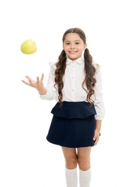 Detox and diet Healthy nutrition diet Girl pupil hold apple fruit on white background Kid happy hold apple School snack concept Apple vitamin snack Schoolgirl wear formal uniform hold apple