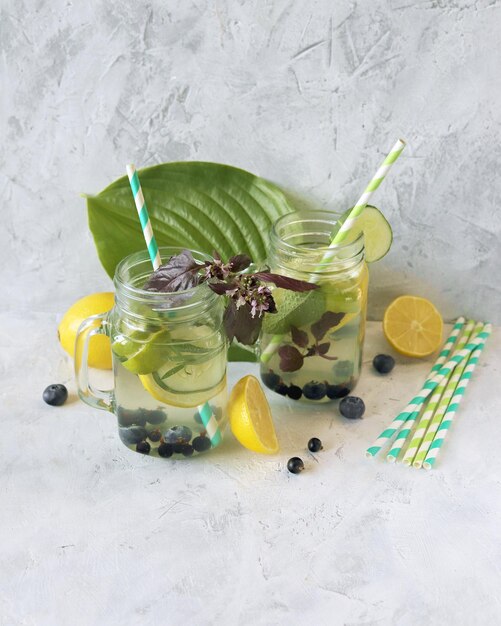 Detox drink made from blueberries citrus fruits cucumber slices and mint leaves in glass jars