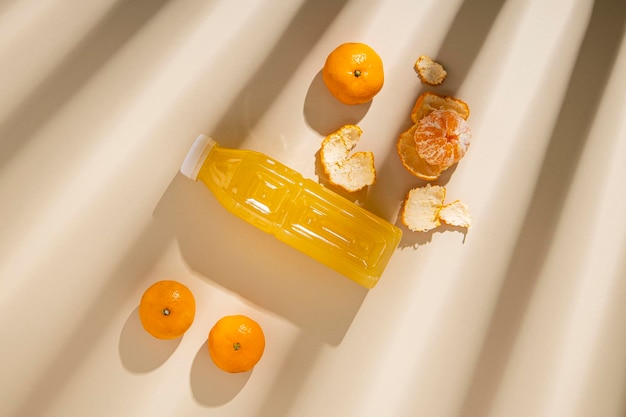 Detox drink in a plastic bottle tangerines under the rays of the sun on a light background Top view flat lay