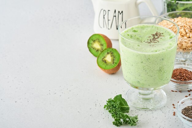 Foto smoothie verde detox con cavolo riccio, spinaci e kiwi su fondo grigio chiaro di ardesia, pietra o cemento. vista dall'alto con copia spazio.