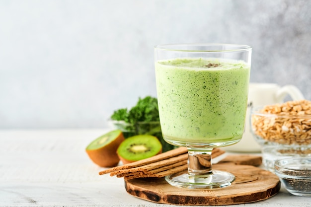 Detox green smoothie with kale, spinach and kiwi on a light gray slate