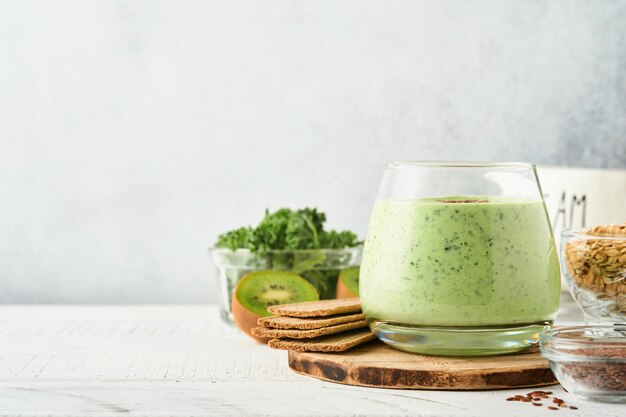 Photo detox green smoothie with kale, spinach and kiwi on a light gray slate