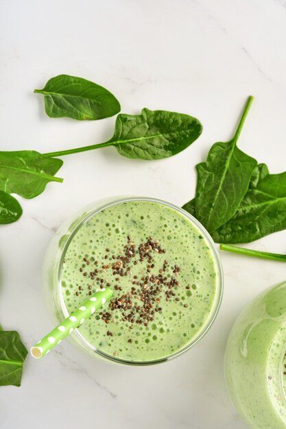 Detox groene smoothie met spinazie, chiazaden en kiwi op een lichtgrijze leisteen