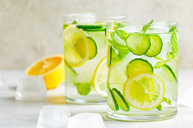 Detox sassy water with cucumber and lemon in glasses, light background. Healthy eating concept.