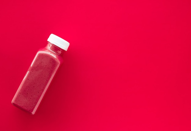 食品と栄養の専門家のブログの赤い背景の flatlay デザインに減量浄化のためのデトックス スーパー フード ストロベリー スムージー ボトル