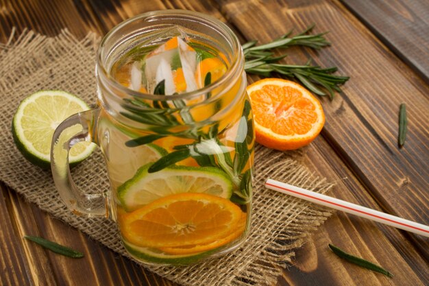 Detox water met mandarijnen, limoen en rozemarijn op de rustieke houten achtergrond