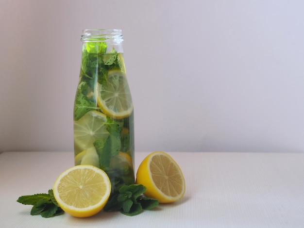 Detox water met schijfjes citroen verse muntblaadjes en plakjes gember in een glazen fles