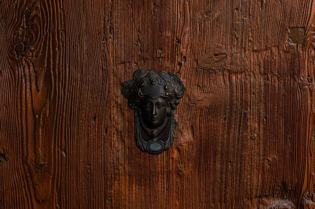 Deurklopper in de vorm van een hoofd op een houten deur
