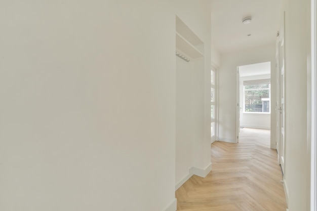 Deuropening van modern appartement met witte muren en parketvloer