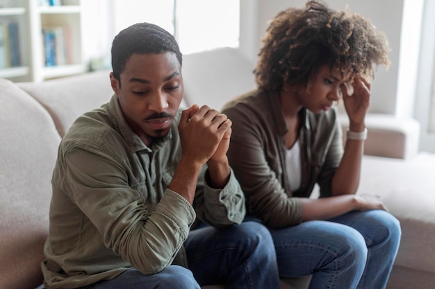 Photo devastated black husband and wife sitting on sofa at home