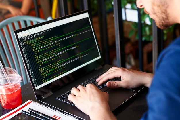 Developer programmer with laptop program code and script data on screen young freelancer in glasses