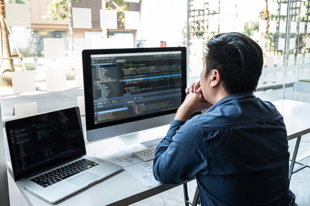 IT会社のオフィスのソフトウェア開発コンピューターでプロジェクトに取り組んでいる開発者プログラマー。コードとデータコードのWebサイトを作成し、データベーステクノロジをコーディングして問題の解決策を見つけます。