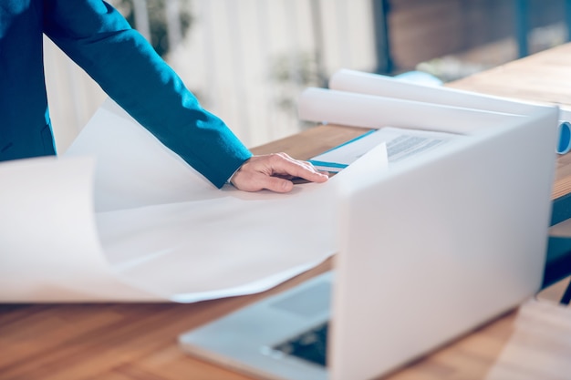 Photo development, analysis. hand of man in dark business jacket holding sheet of paper with diagram lying on office table, face is not visible