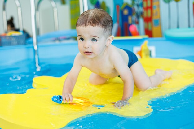 赤ちゃんの発達 小さな男の子がプールで泳ぎを学んでいる 子どもたちの初めての水泳レッスン 赤ちゃんの発達