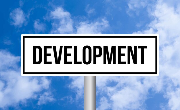 Development road sign on cloudy sky background