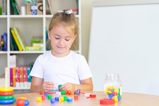 Developmental and speech therapy classes with a child. Speech therapy exercises and games with beads.