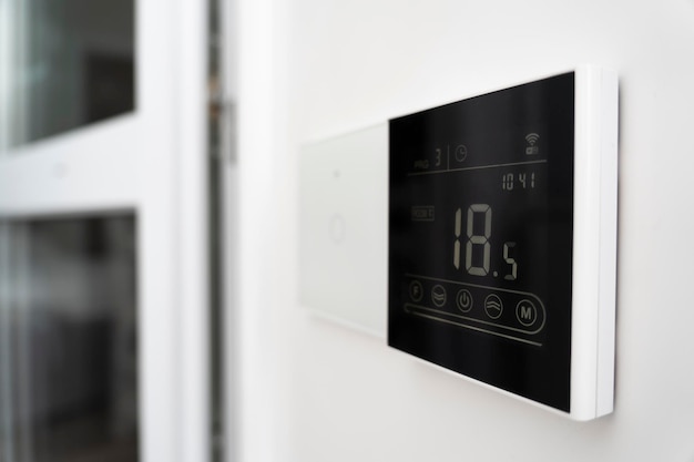 A device for controlling underfloor heating air conditioner screen on wall that shows an air temperature of 18 degrees Celsius