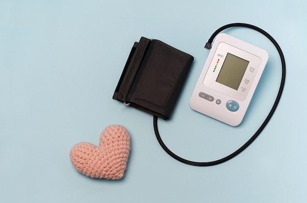 Photo a device for measuring pressure a tonometer on a blue medical background and a knitted heart