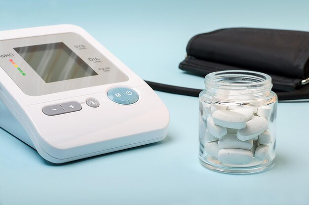 A device for measuring pressure, tonometer on a blue medical background and a number of white pills