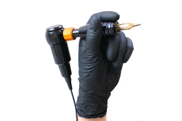 Device for tattooing. tattoo tool on a white isolated background is in a hand in black gloves.