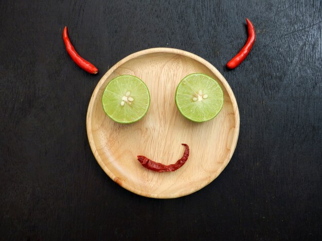 Devil smile, wooden plate is face, lemon slice is eye, red dry chili is mouth and red chil