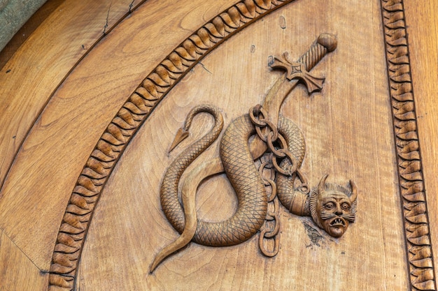 悪魔のヘビのシンボルイタリアの古いドアの12世紀の修道院のファンタジー魔法の生き物