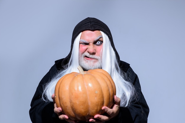 Devil vampire man happy halloween evil wizard hold orange pumpkin mature man magician in witch hat