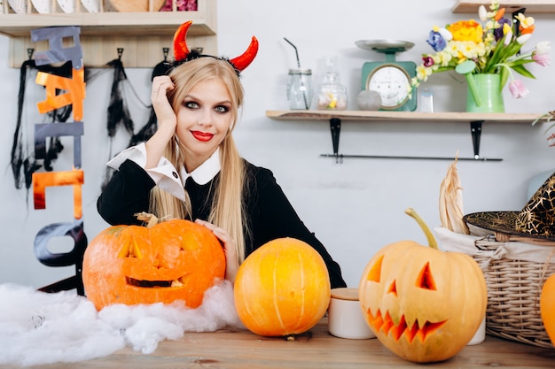 カボチャのハロウィーンのテーブルに座っている悪魔の女性