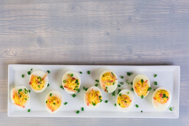 Deviled eggs garnished with green onions and bacon.