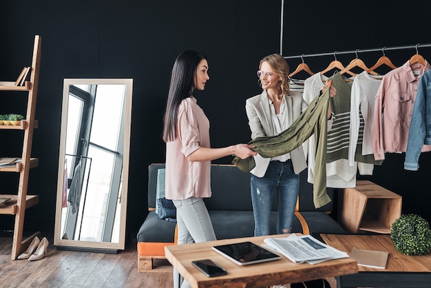 Deze is perfect voor jou. Mooie jonge vrouw helpt bij het kiezen van kleding voor haar klant