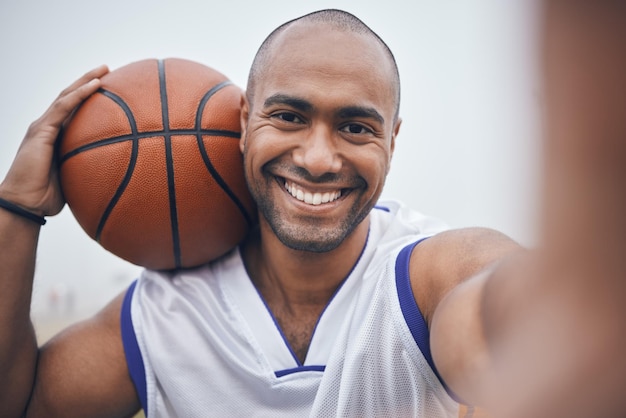 Deze komen in mijn catalogus. Shot van een jonge mannelijke basketballer die een selfie maakt terwijl hij de bal vasthoudt