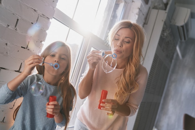 Dezelfde hobby delen. moeder en dochter hebben plezier met zeepbellen terwijl ze thuis tijd doorbrengen