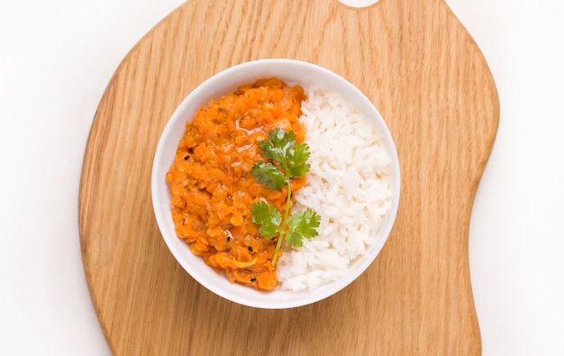 Dhal Indian lentil soup with rice and herbs in a white bowl on a wooden board