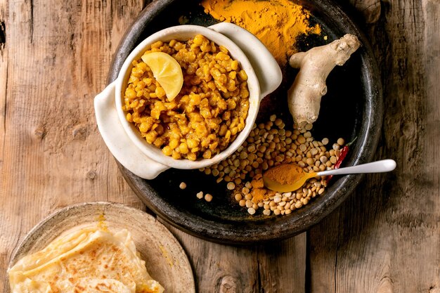 Dhal with roti bread Traditional indian yellow pea vegan food dal with roti flatbread served with lemon in ceramic bowl on old wooden table Flat lay copy space