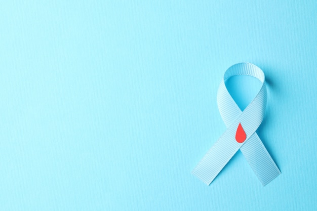 Diabetes. Blue awareness ribbon with decorated blood drop on blue background