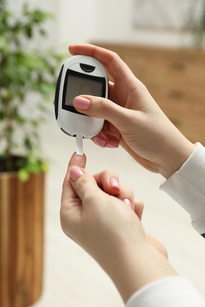 Diabetes Woman checking blood sugar level with glucometer at home closeup