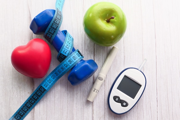 Diabetic measurement tools and dumbbell and apple on table