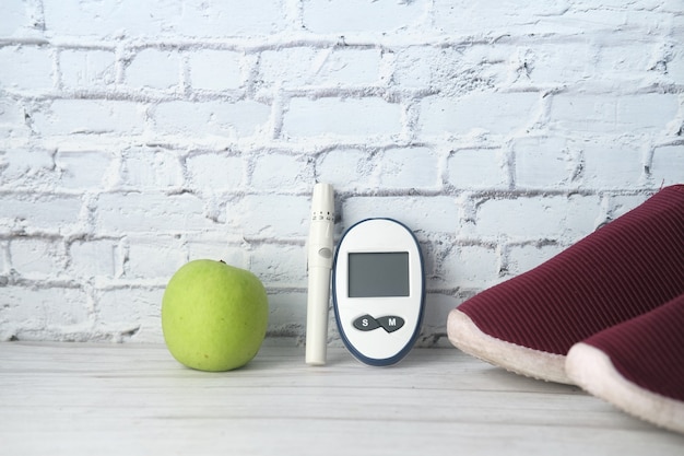 diabetic measurement tools, shoe and apple on table