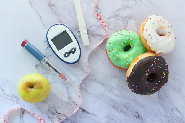 Foto diabetische meetinstrumenten insuline en donuts op witte achtergrond