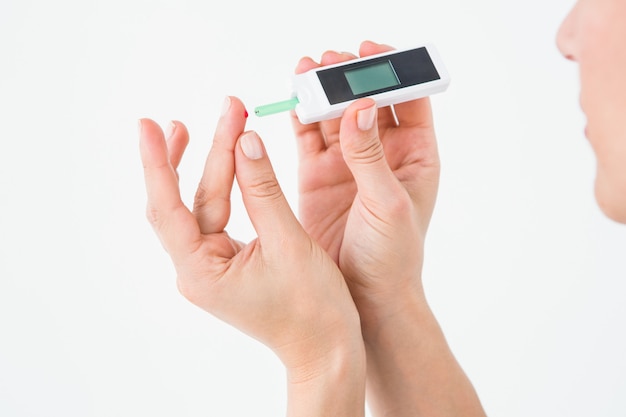 Diabetische vrouw die de monitor van de bloedglucose op witte achtergrond gebruikt