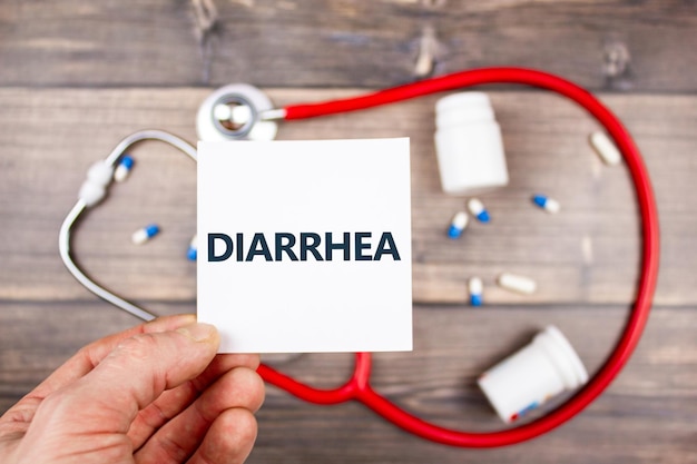 Диагноз концепция диарея Мужчина держит в руке лист со словом диарея на фоне таблеток Молочное лечение