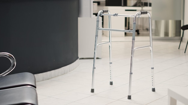 Photo diagnostic center with reception counter, walking frame placed in empty hospital lobby with registration front desk. medical health care facility with chairs and consultation checkup.