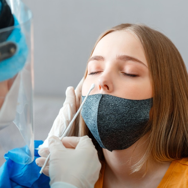 Foto diagnostiek die patiënten coronavirus covid 19 test arts met beschermend medisch masker die pcr-test nasofaryngeale cultuur doet bij vrouw verpleegkundige neemt speekselmonstertest door neus met wattenstaafje
