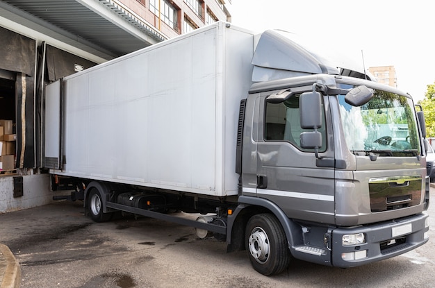 Photo diagonak view of gray truck delivering food products into shop