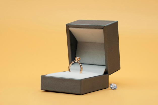 Diamond ring in jewelry gift box on yellow background